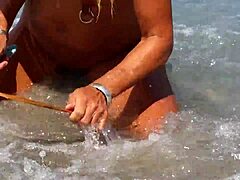 Zralá žena s roztaženými piercingy na bradavkách a několika piercingy v kundičce na pláži