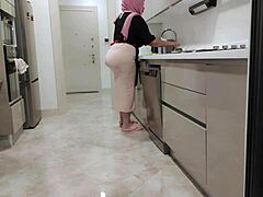De grote borsten van een stiefmoeder stuiteren terwijl ze kookt voor haar stiefzoon
